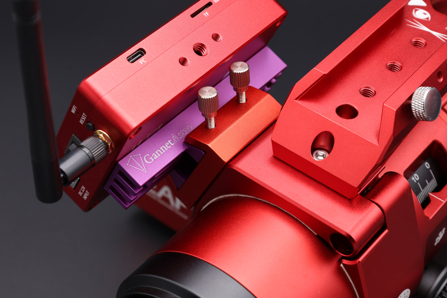 Close-up of a dedicated astrophotography computer mounted to the Gannet Astro mounting bracket, attached to a telescope.  The computer is red, the bracket is purple, the telescope is red.