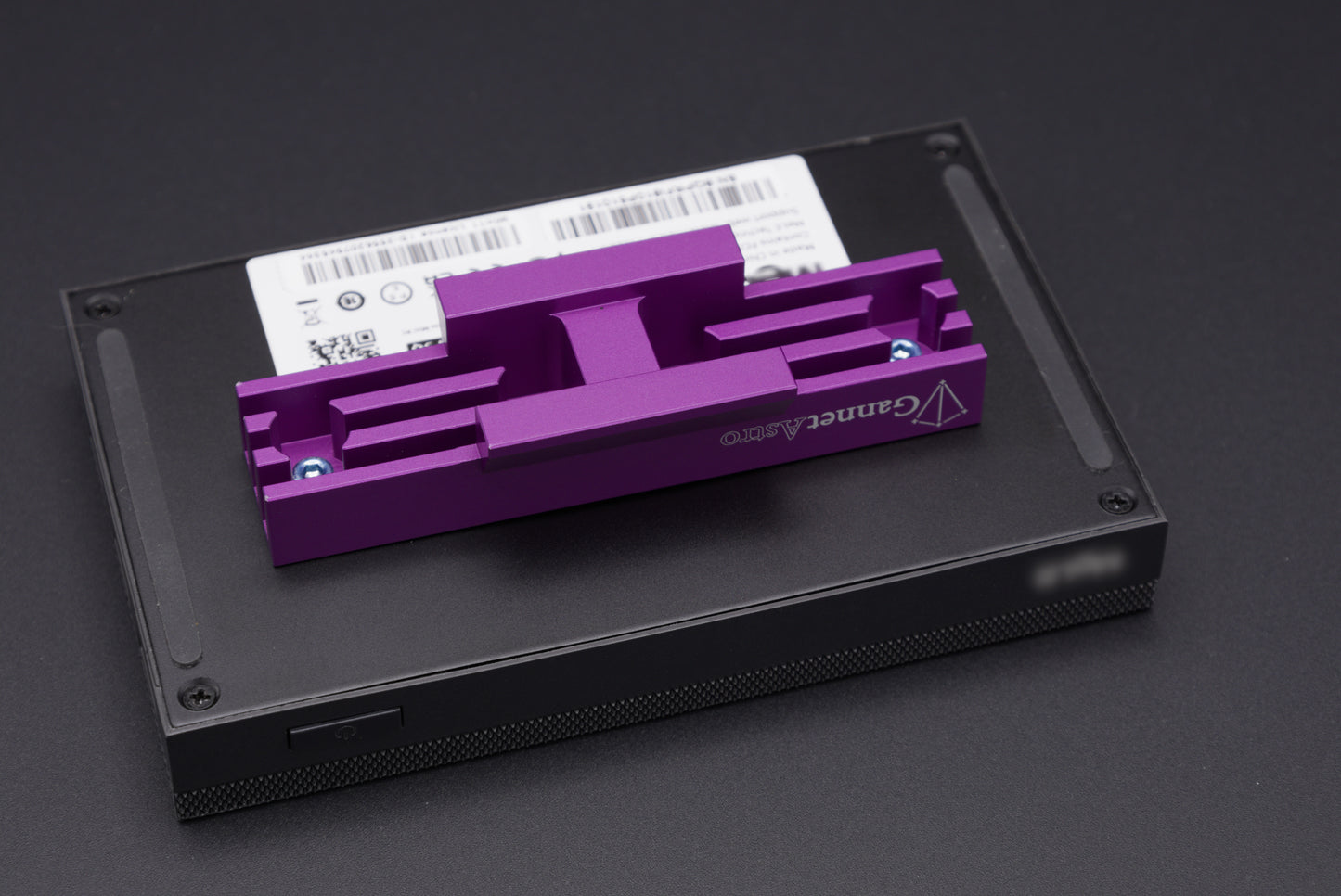 Close-up of a mini PC with the Gannet Astro mounting bracket attached.  The computer is black, the bracket is purple.